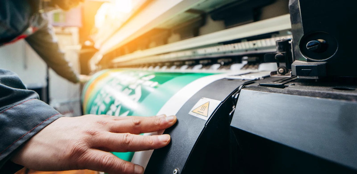 Hand adjusting a roll on the wide-format printer at The Print Doctor